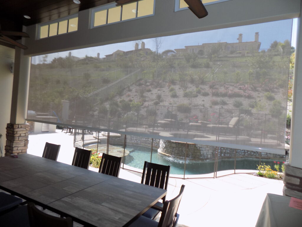 Covered patio with retractable shade, pool, and hillside view.