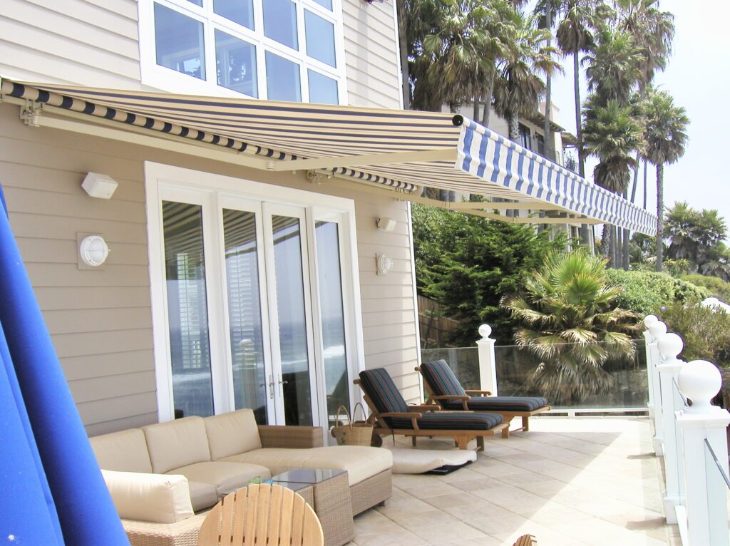 Striped awning patio with trees and palms.